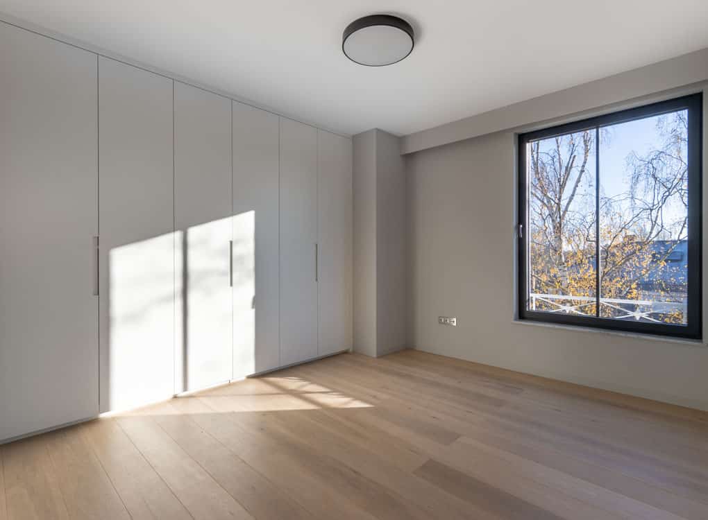 Intérieur moderne minimaliste avec lumière naturelle, murs gris, sol en bois, et fenêtres élégantes