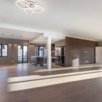 Intérieur contemporain lumineux avec cuisine élégante, sol en bois, grandes fenêtres et éclairage moderne.