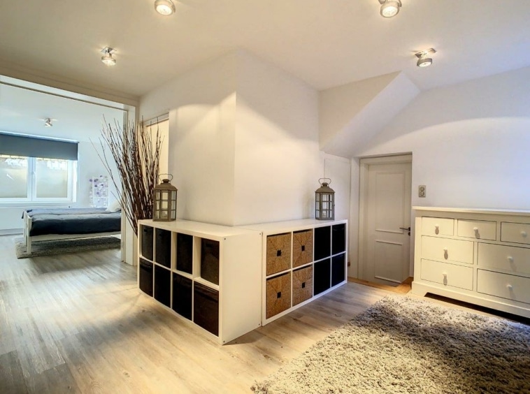 Intérieur moderne avec rangement élégant, murs blancs, bois clair, décoration florale et lanternes rustiques.