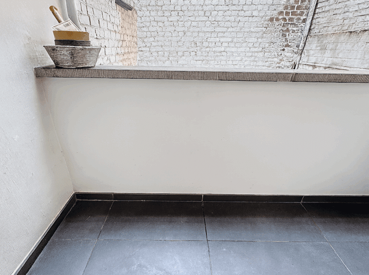 Espace moderne avec mur en briques, plan en granit clair et sol en carrelage foncé.