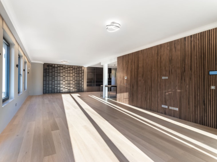 Espace moderne lumineux avec sol en bois clair et mur en lattes de bois verticales texturées.