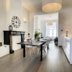 Salon moderne lumineux avec cheminée, mobilier épuré et éclairage design, ambiance chaleureuse.