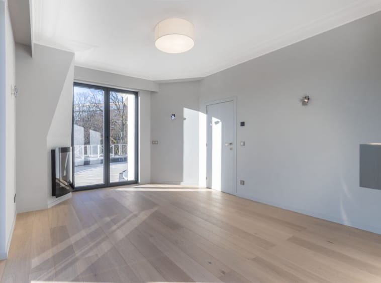 Salon moderne minimaliste avec cheminée, grandes fenêtres et éclairage naturel chaleureux.