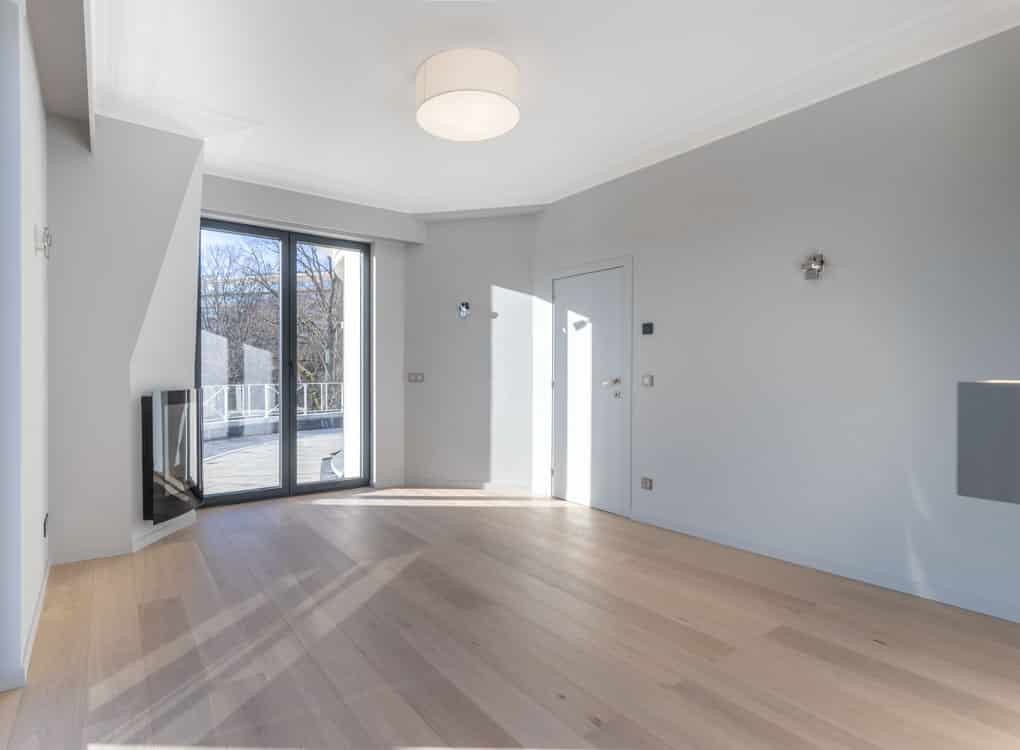 Salon moderne minimaliste avec cheminée, grandes fenêtres et éclairage naturel chaleureux.