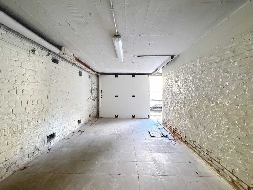 Passage industriel vintage avec murs en briques blanches, porte entrouverte, ambiance minimaliste.