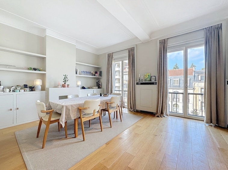 Salle à manger moderne lumineuse avec balcon, mobilier en bois clair, plantes et décoration élégante.