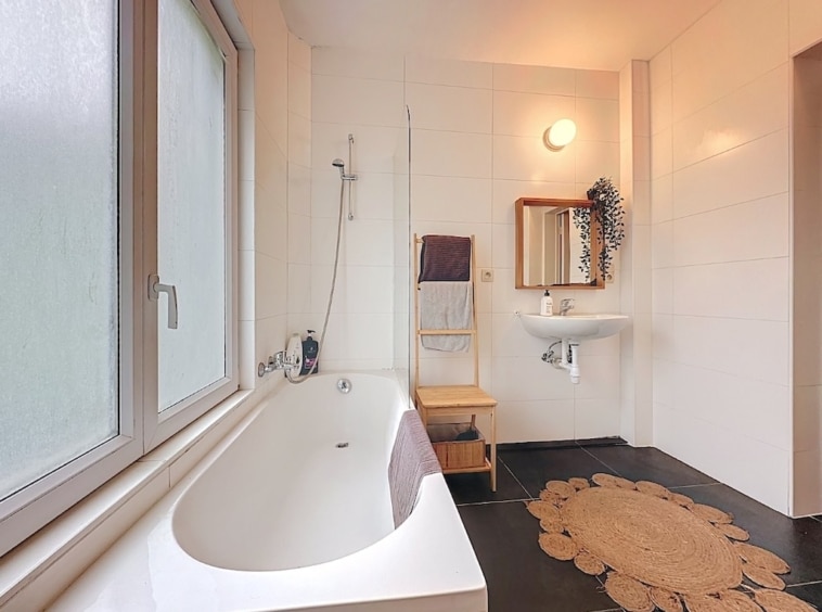 Salle de bain moderne minimaliste avec baignoire indépendante, douche, touches en bois et ambiance apaisante.