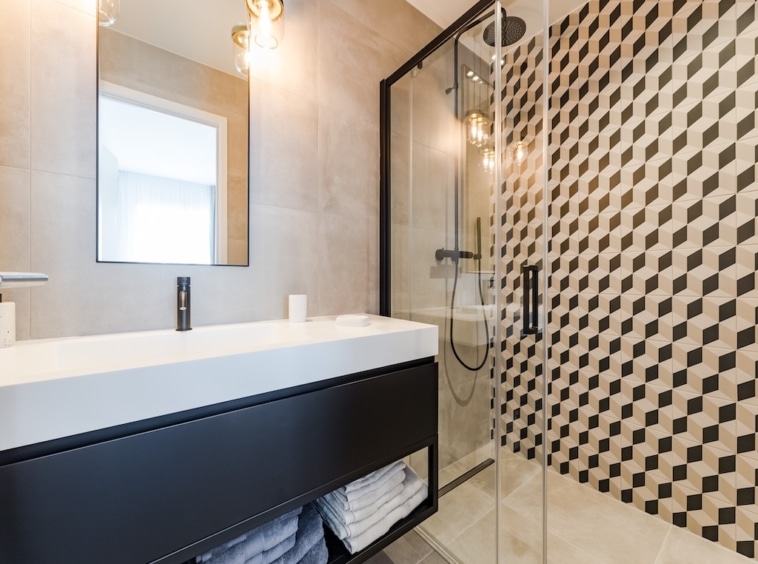 Salle de bain moderne, épurée, lumineuse avec mobilier minimaliste, douche en verre et éclairage chaleureux.