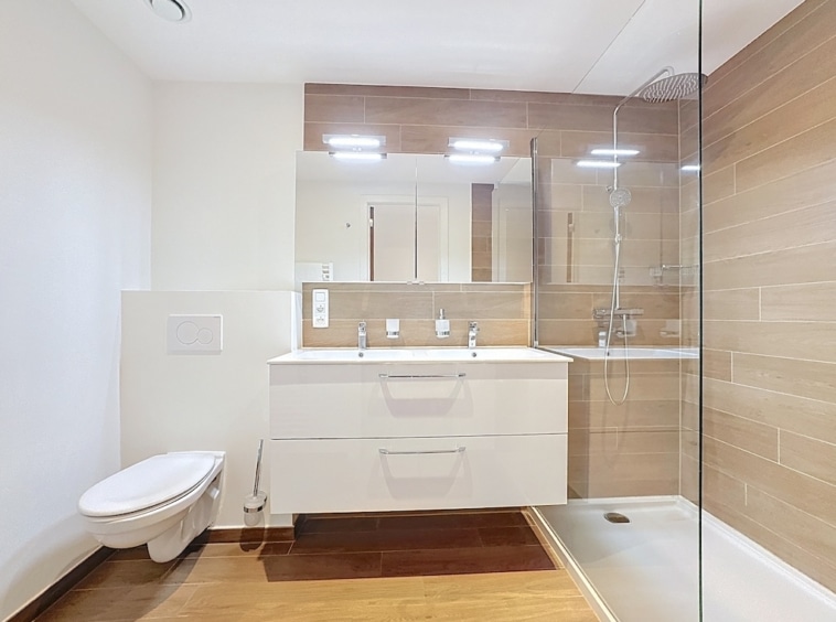 Salle de bain moderne, double vanité blanche, douche en verre, ambiance lumineuse et élégante.