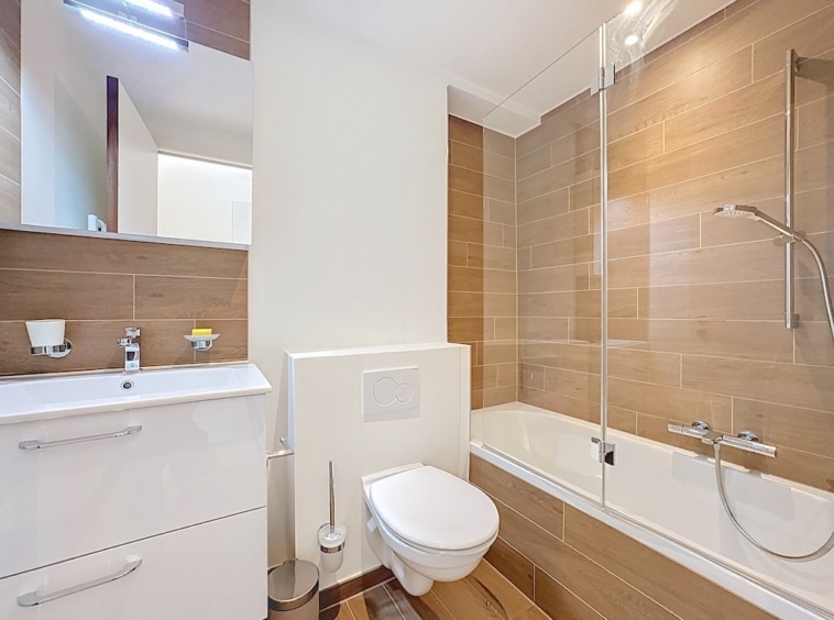 Salle de bain moderne en bois chaleureux, lumineux avec douche, lavabo, WC design et ambiance épurée.