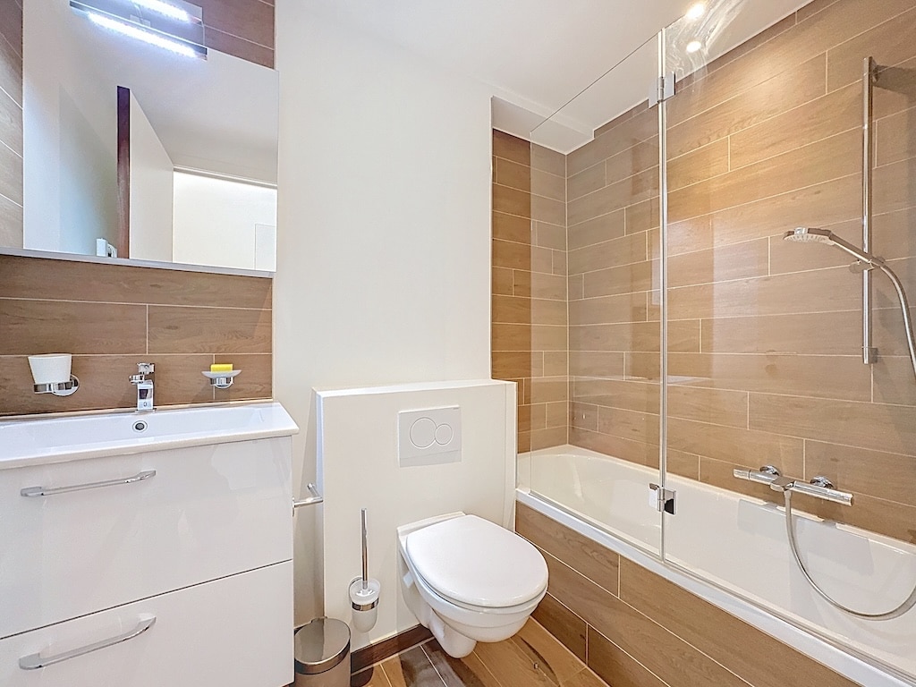 Salle de bain moderne en bois chaleureux, lumineux avec douche, lavabo, WC design et ambiance épurée.