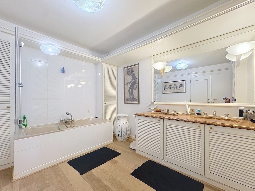 Salle de bain moderne élégante avec baignoire, grand miroir et décoration raffinée.