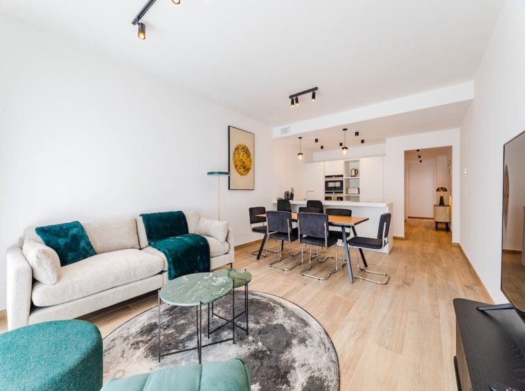 Salon contemporain lumineux avec canapé, espace repas élégant, décoration moderne et lumière naturelle.
