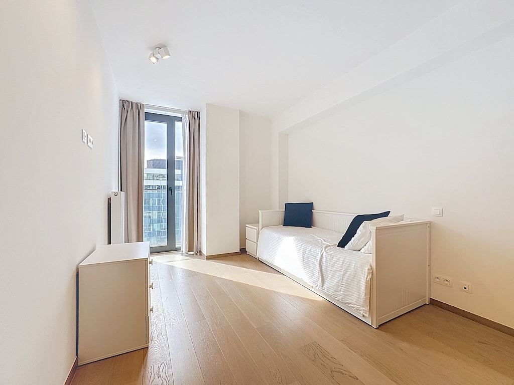 Salon lumineux minimaliste avec canapé blanc, lumière naturelle et mobilier épuré pour relaxation.