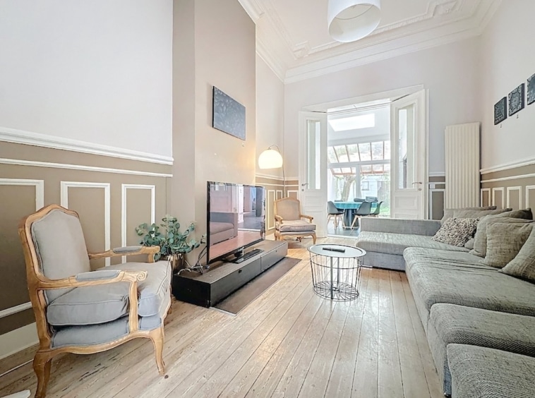 Salon lumineux et élégant avec mobilier moderne, moulures classiques et décoration raffinée.