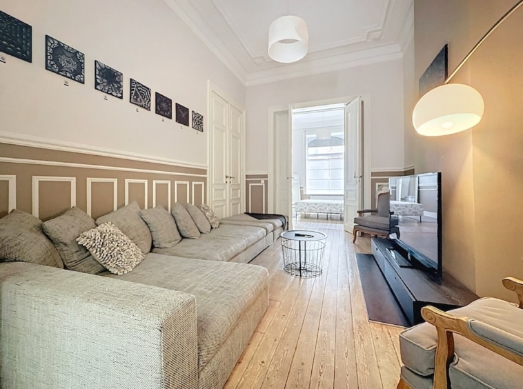Salon moderne et cosy avec canapé gris, art mural, lumière naturelle et déco élégante.