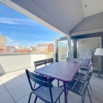 Terrasse urbaine accueillante avec mobilier moderne, vue sur les toits et ambiance détendue.
