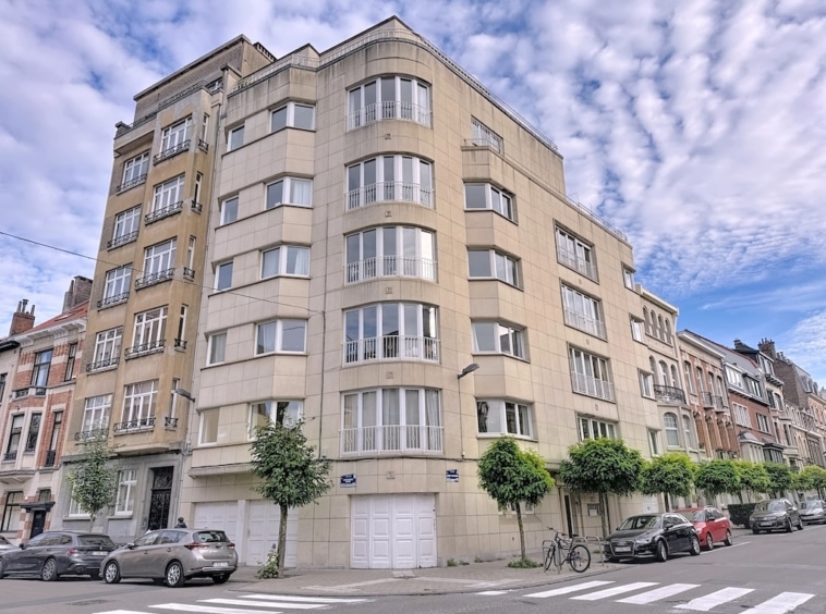 Résidence moderne à quatre étages avec balcons courbes, grandes fenêtres et verdure chaleureuse.