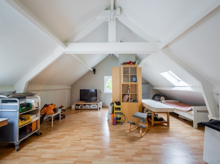Attique lumineuse et cosy avec poutres en bois, espace détente, lit simple, lumière naturelle abondante.