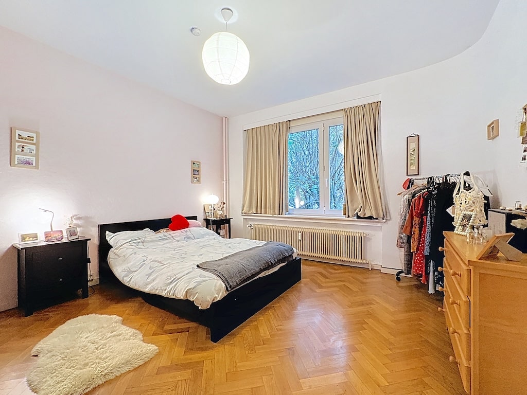 Chambre lumineuse, chaleureuse et élégante avec lit en bois, décoration cosy et vue verdoyante.
