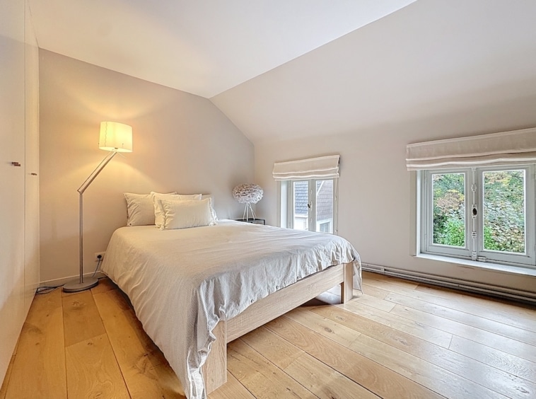 Minimalistische moderne slaapkamer, zachte verlichting, natuurlijk licht, uitzicht op de natuur, serene sfeer.