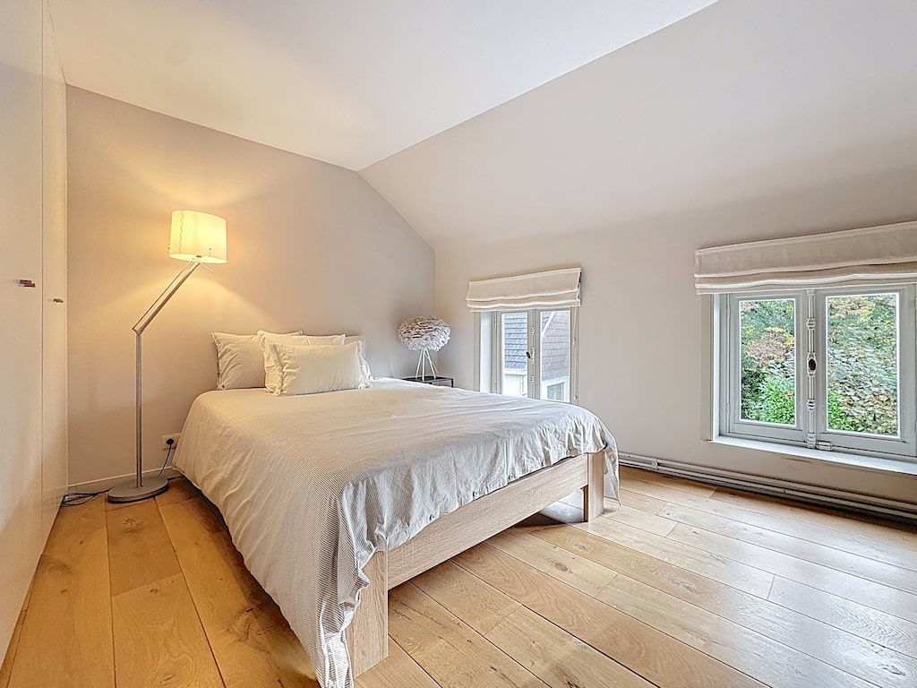 Minimalistische moderne slaapkamer, zachte verlichting, natuurlijk licht, uitzicht op de natuur, serene sfeer.