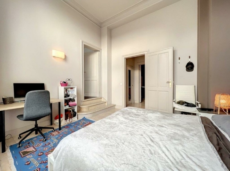 Chambre lumineuse moderne avec lit blanc, espace de travail organisé et ambiance chaleureuse.