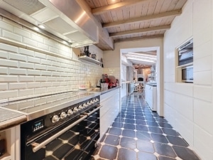 Modern kitchen with stainless steel cooktop, wooden beams, black floor and bright decor.