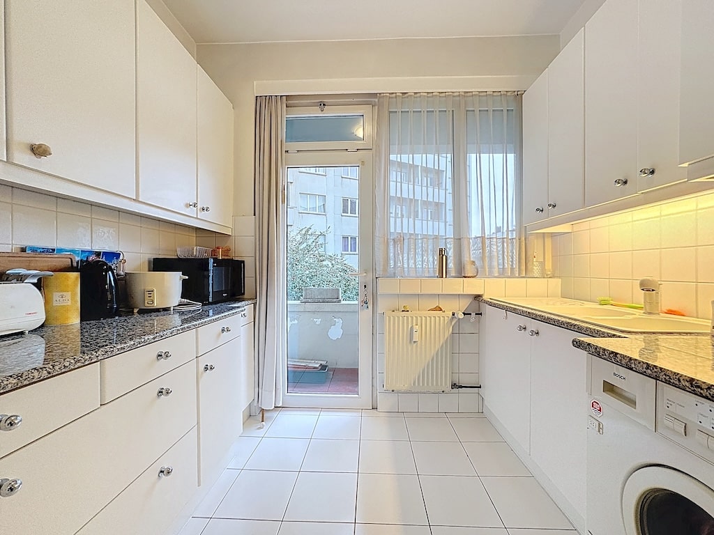 Cuisine moderne et lumineuse avec balcon, électroménagers intégrés et style épuré.