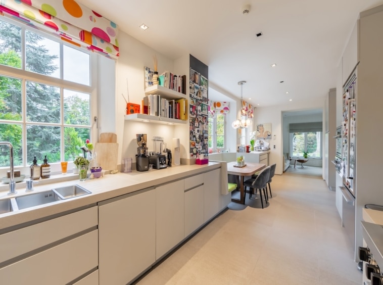 Cuisine moderne lumineuse avec mobilier gris, espace repas coloré et ambiance chaleureuse.