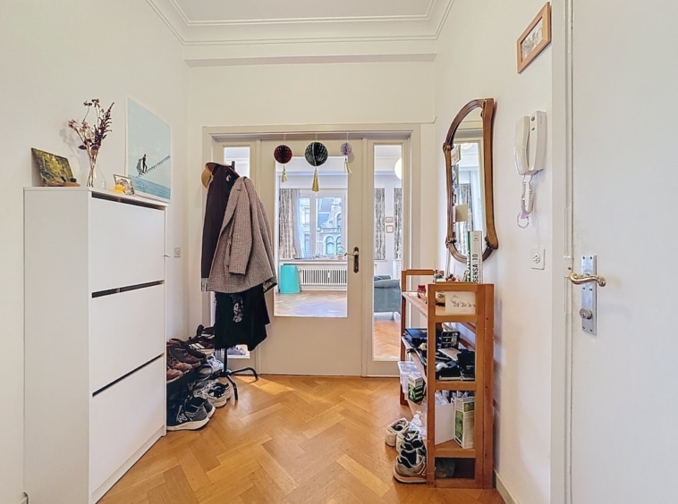 Entrée lumineuse avec mobilier en bois, miroir vintage, porte-vêtements, décorations élégantes.