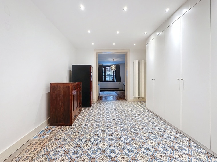 Hall moderne avec tuiles colorées, rangement élégant, et vue sur salon lumineux.