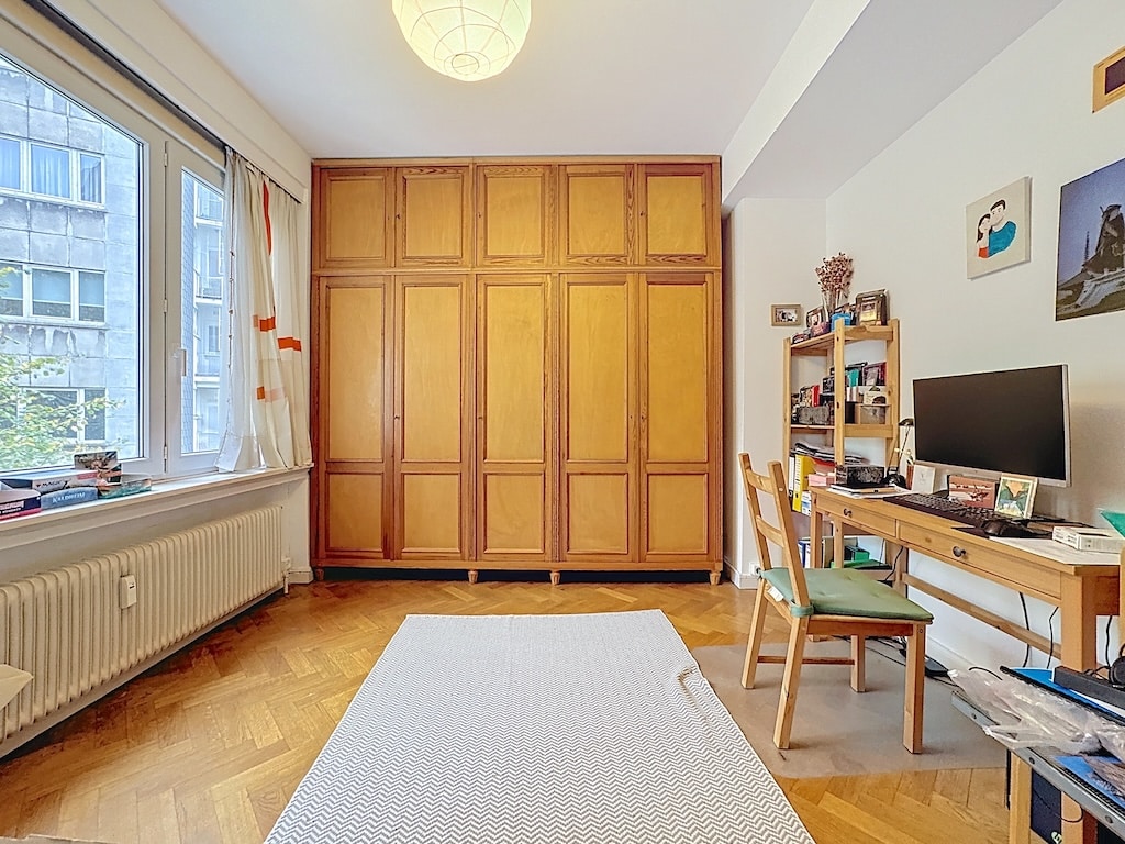 Intérieur chaleureux avec grand placard en bois, coin bureau, tapis, lumières douces et œuvres d’art.