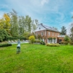 Gezellig bakstenen huis met tuin, paardensculptuur, zwembad en herfstsfeer.