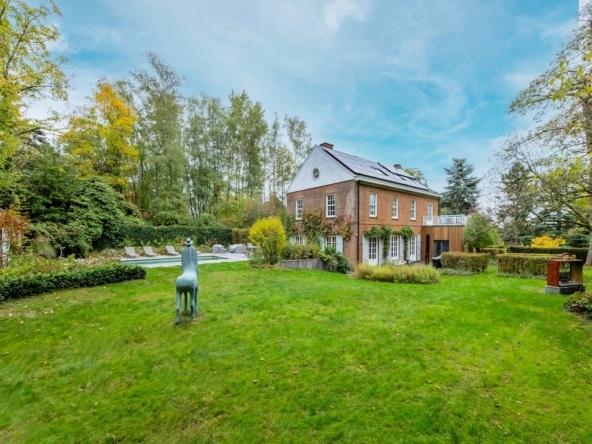 Maison chaleureuse en briques avec jardin, sculpture de cheval, piscine et ambiance automnale.