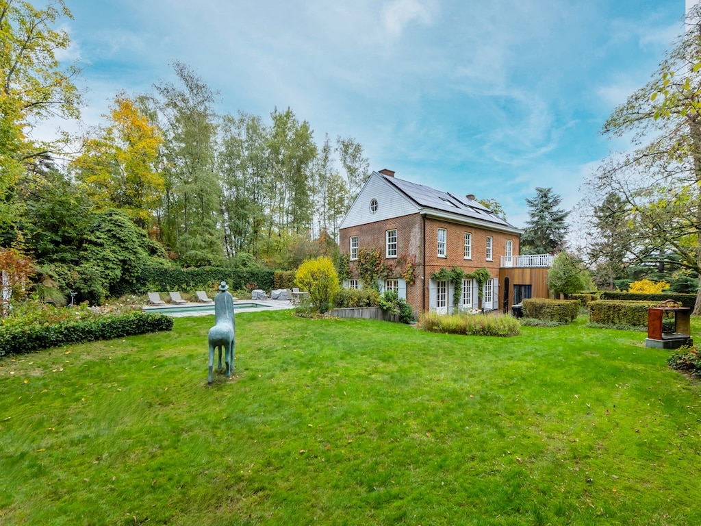 Gezellig bakstenen huis met tuin, paardensculptuur, zwembad en herfstsfeer.