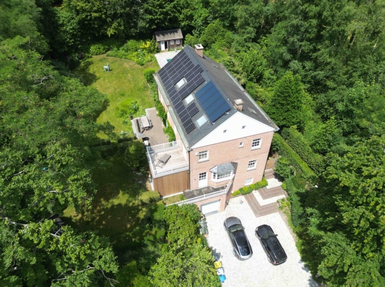 Maison écologique moderne avec panneaux solaires, jardin verdoyant, parking et espace détente.