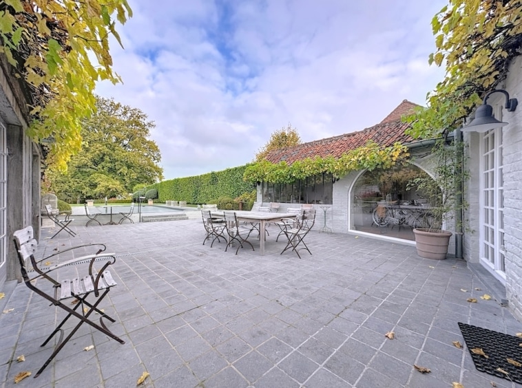 Elegante stenen patio, lommerrijke tuin, modern meubilair, rustige omgeving om te ontspannen of te dineren.