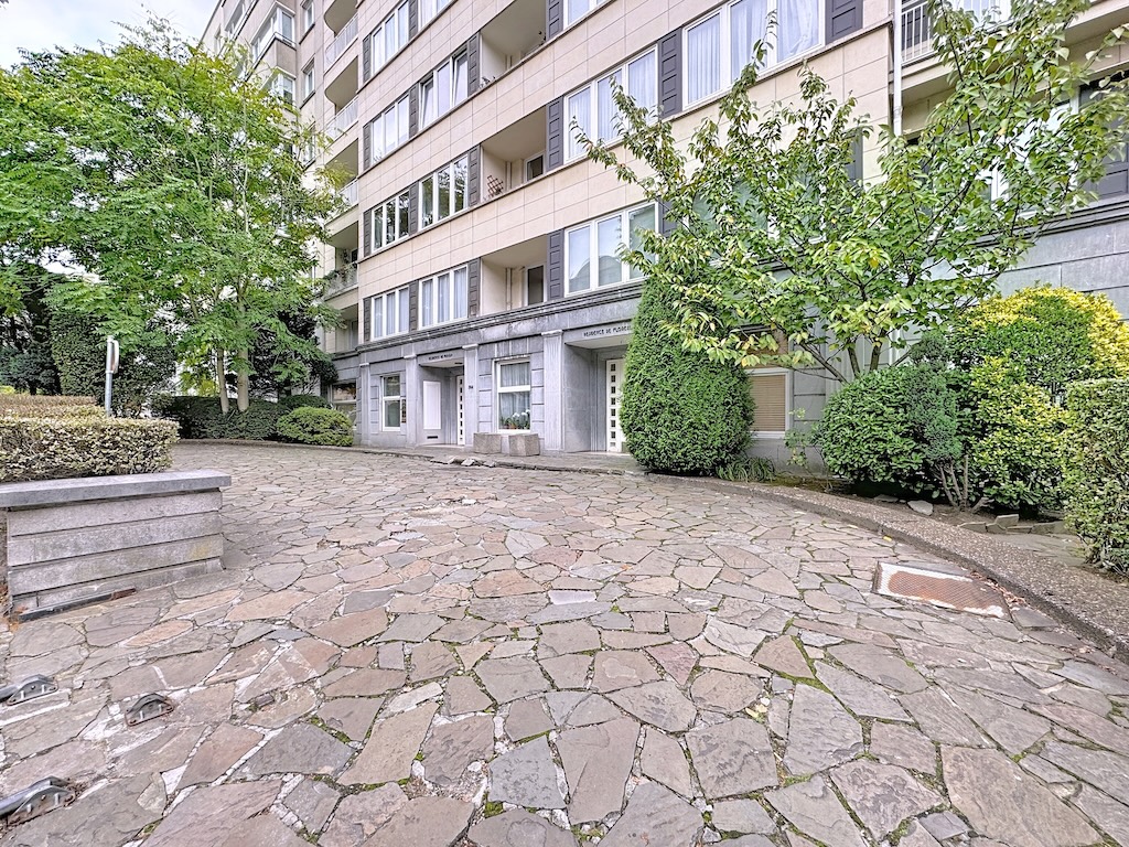 Résidence moderne entourée de verdure, avec chemin en pierres naturelles et espaces de détente.
