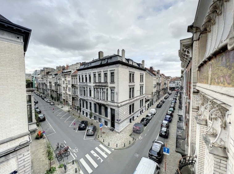 Rue pavée élégante avec bâtiments classiques, voitures stationnées, ambiance urbaine raffinée et paisible.