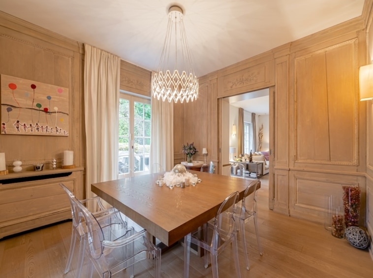 Salle à manger moderne avec bois, chaises transparentes et lustre en cristal sophistiqué.