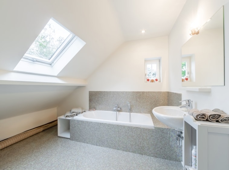 Salle de bain moderne minimaliste avec baignoire en pierre, lavabo sleek, lumière naturelle, ambiance sereine.