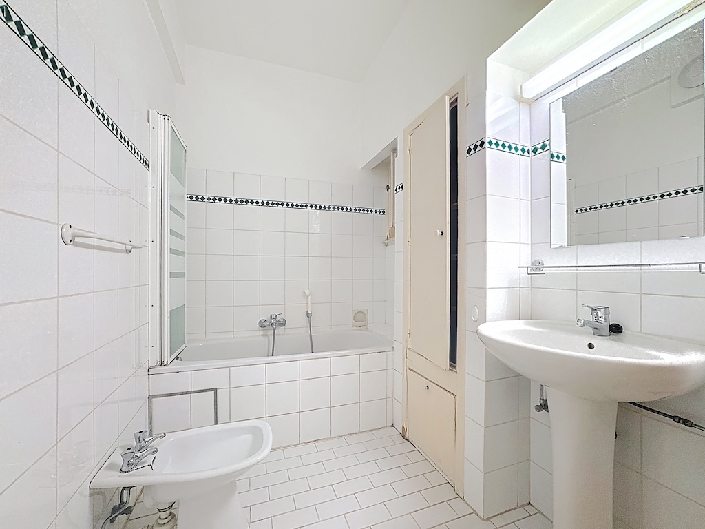 Salle de bain moderne épurée avec baignoire, douche en verre et miroir lumineux.