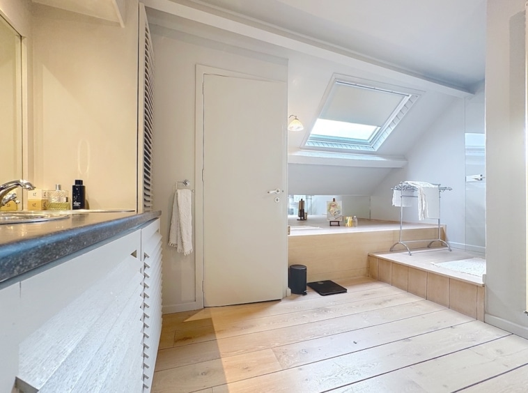 Heldere moderne badkamer met jacuzzi, elegant badmeubel, natuurlijk licht en strak design.