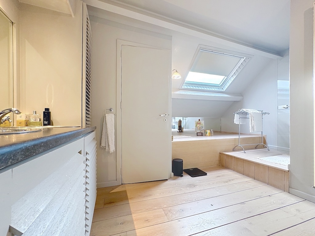 Heldere moderne badkamer met jacuzzi, elegant badmeubel, natuurlijk licht en strak design.