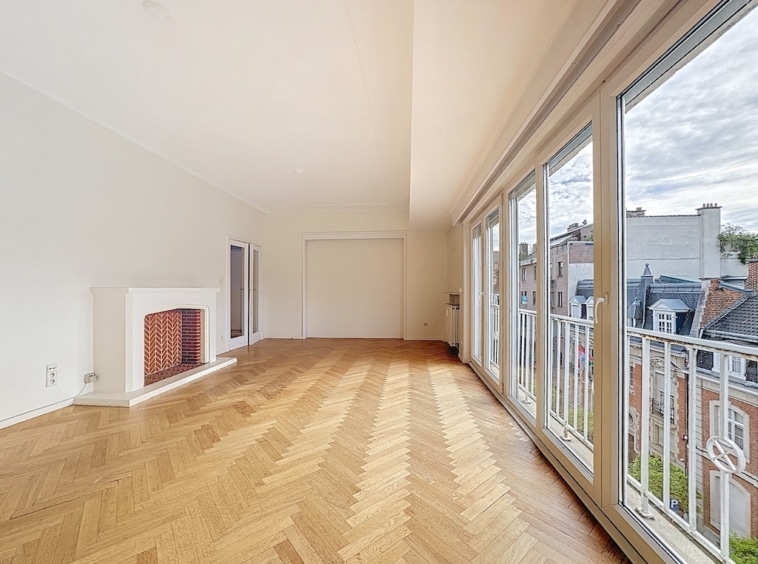 Salle lumineuse avec vue panoramique, parquet en chevrons, cheminée moderne et ambiance élégante.