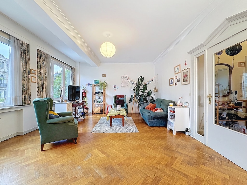 Salon cosy avec canapé bleu, fauteuil vert, lumière naturelle et décoration colorée.