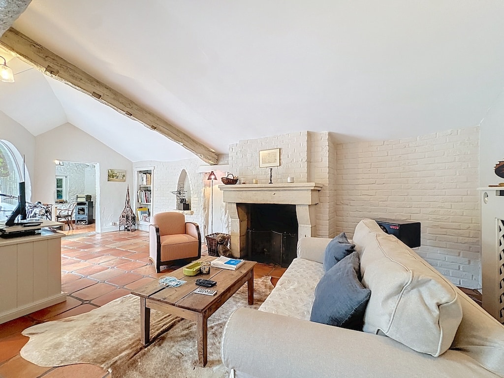 Gezellige woonkamer met open haard, beige bank, pastel fauteuil en moderne rustieke uitstraling.