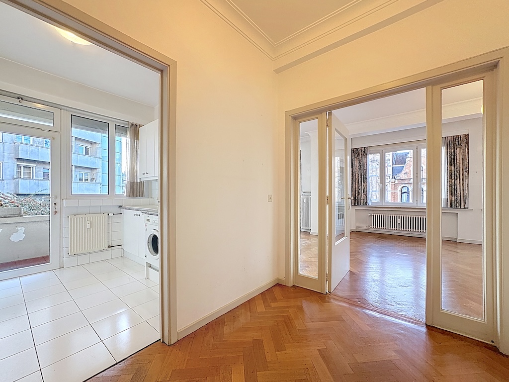 Salon et cuisine lumineux avec espace ouvert, parquet en bois et décoration moderne chaleureuse.