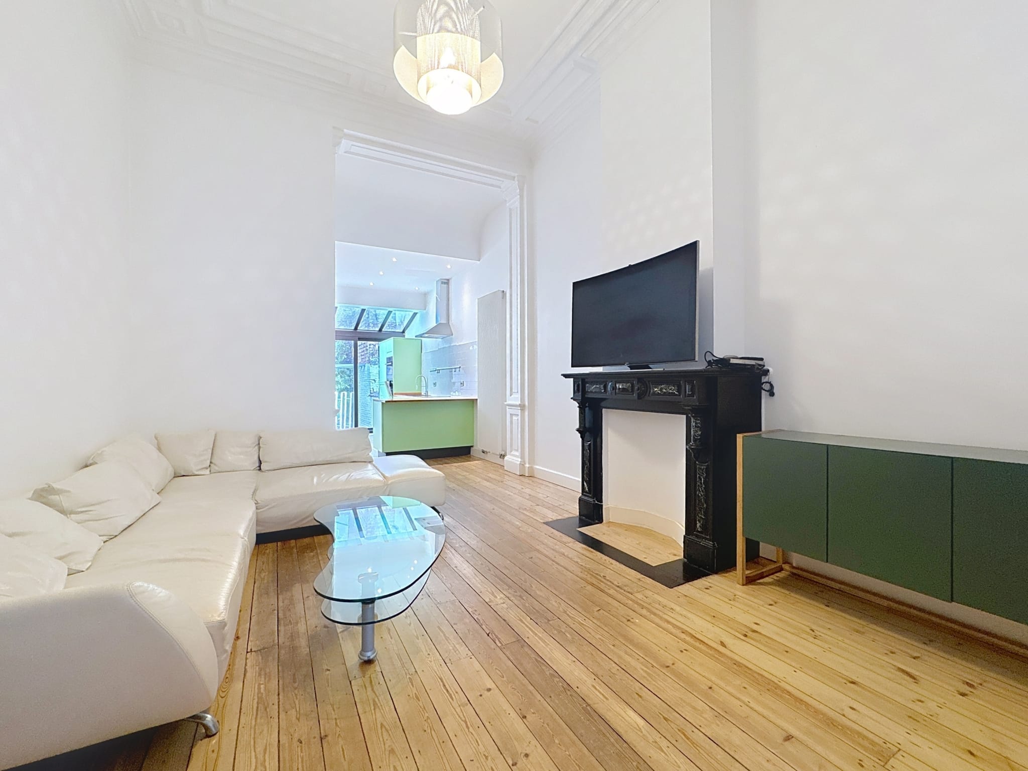 Salon lumineux et moderne avec cheminée noire, vue naturelle et mobilier épuré.